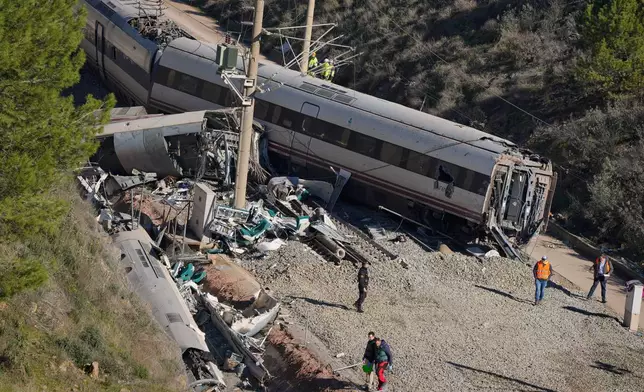 Guardia Civil officers collect evidence next to the wreckage of train cars involved in a collision in Adamuz, southern Spain, Tuesday, Jan. 20, 2026. (AP Photo/Manu Fernandez)