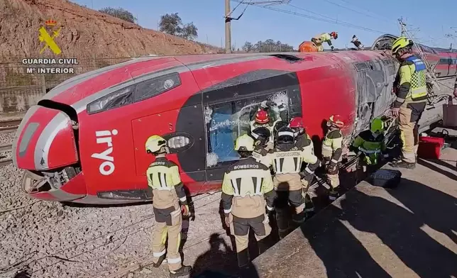 In this grab taken from video provided by Guardia Civil, rescue workers at the scene following a high-speed train collision, in Adamuz, Spain, Monday, Jan. 19, 2026. (Guardia Civil via AP)