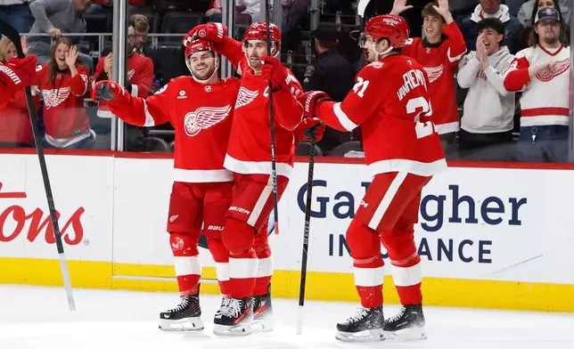 Detroit Red Wings right wing Alex DeBrincat, left, celebrates with center Dylan Larkin, center, and left wing James van Riemsdyk after scoring against the San Jose Sharks during the first period of an NHL hockey game, Friday, Jan. 16, 2026, in Detroit. (AP Photo/Duane Burleson)