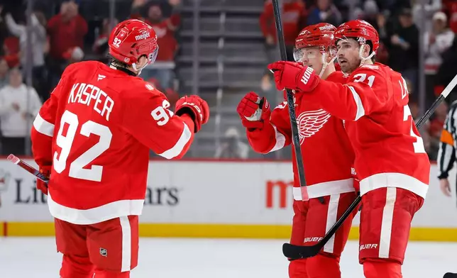 Detroit Red Wings center Marco Kasper (92) celebrates with left wing Lucas Raymond, center, and center Dylan Larkin, right, after Kasper's open-net goal against the San Jose Sharks during the third period of an NHL hockey game Friday, Jan. 16, 2026, in Detroit. (AP Photo/Duane Burleson)