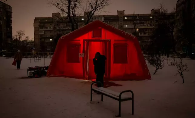 A man smokes outside of an emergency tent where people can warm up following Russia's regular air attacks against the country's energy objects, that leave residents without power, water and heating in the dead of winter, in Kyiv, Ukraine, Tuesday, Jan. 13, 2026. (AP Photo/Danyil Bashakov)