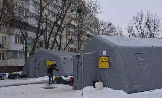 A man gets warm at emergency tents where people can warm up following Russia's regular air attacks against the country's energy objects, that leave residents without power, water and heating in the dead of winter, in Kyiv, Ukraine, Tuesday, Jan. 13, 2026. (AP Photo/Efrem Lukatsky)