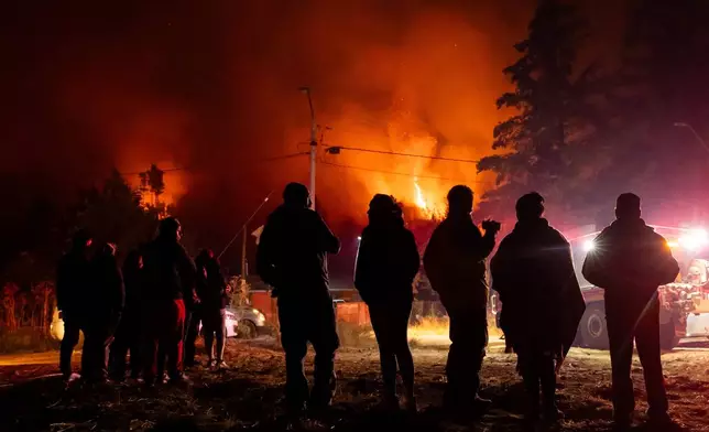 Residents look out at wildfires by their homes near Concepcion, Chile, Monday, Jan. 19, 2026. (AP Photo/Javier Torres)