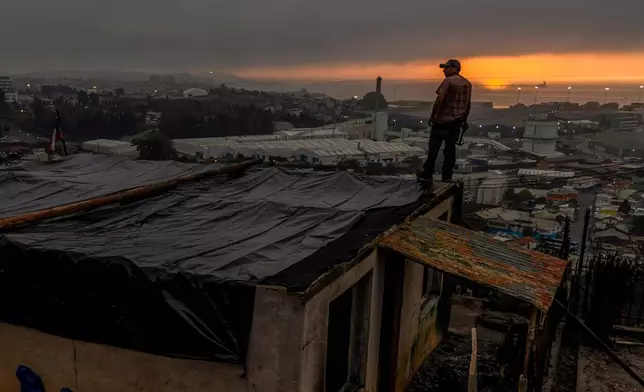 Jonathan Escalona stands over his house damaged by wildfires in Lirquen, Chile, Tuesday, Jan. 20, 2026. (AP Photo/Javier Torres)
