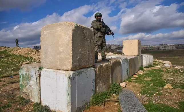 Israeli soldiers stand guard during a ceremony for a newly-legalized Jewish settlement, Yatziv, adjacent to the Palestinian town of Beit Sahour, in the West Bank, Jan. 19, 2026. (AP Photo/Ohad Zwigenberg)