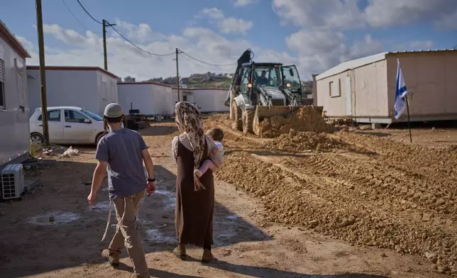 Israeli settlers walk through the newly-legalized Jewish settlement of Yatziv, adjacent to the Palestinian town of Beit Sahour, in the West Bank, Jan. 19, 2026. (AP Photo/Ohad Zwigenberg)