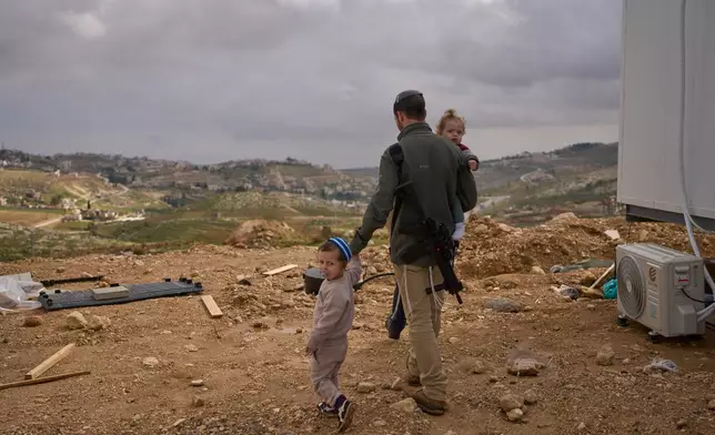 An Israeli settler and his children walk through the newly-legalized Jewish settlement, Yatziv, adjacent to the Palestinian town of Beit Sahour, in the West Bank, Jan. 19, 2026. (AP Photo/Ohad Zwigenberg)