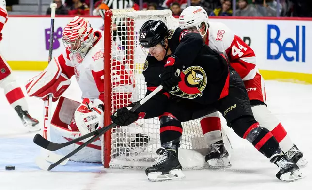 Ottawa Senators' Fabian Zetterlund (20) tries to wrap the puck around Detroit Red Wings' goaltender John Gibson, left, (36) during second-period NHL hockey game action in Ottawa, Ontario, Monday, Jan. 5, 2026. (Spencer Colby/The Canadian Press via AP)