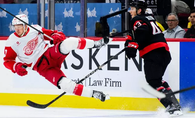 Detroit Red Wings' Lucas Raymond (23) is tripped by Ottawa Senators' Tyler Kleven (43) during second-period NHL hockey game action in Ottawa, Ontario, Monday, Jan. 5, 2026. (Spencer Colby/The Canadian Press via AP)