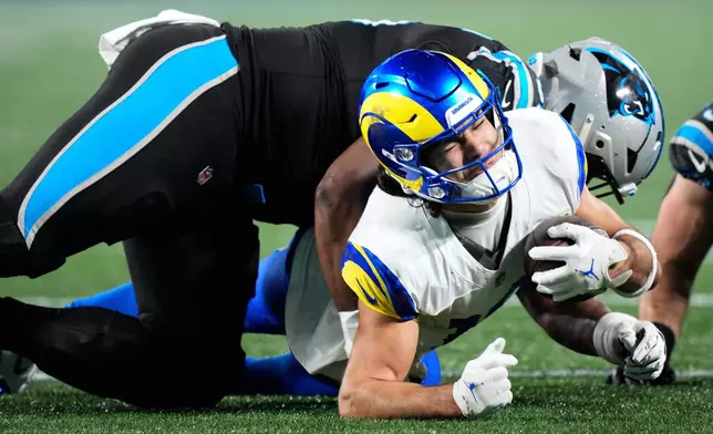 Los Angeles Rams wide receiver Puka Nacua, bottom, is tackled by Carolina Panthers defensive end Derrick Brown during the second half of an NFL wild-card playoff football game, Saturday, Jan. 10, 2026, in Charlotte, N.C. (AP Photo/Jacob Kupferman)