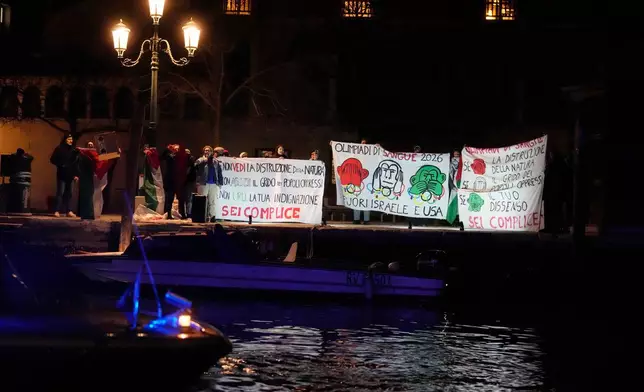 A small group of anti-war activists protest the participation of Israel and the US in the Milan Cortina Olympic Games as the Olympic flame glides down the Grand Canal in Venice, Italy, its journey will conclude in Milan on February 6 for the Winter Olympics opening ceremony. (AP Photo/Luca Bruno)