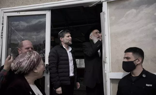 Israeli finance minister Bezalel Smotrich watches Rabbi Amiel Sternberg affix a mezuzah in the newly-legalized Jewish settlement, Yatziv, adjacent to the Palestinian town of Beit Sahour, in the West Bank, Jan. 19, 2026. (AP Photo/Ohad Zwigenberg)