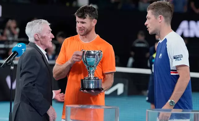 Ken Rosewall, left, presents the trophy to Christian Harrison of the U.S. and Neal Skupski, right, of Britain after they defeated Australia's Jason Kubler and Marc Polmans in the men's doubles final at the Australian Open tennis championship in Melbourne, Australia, Saturday, Jan. 31, 2026. (AP Photo/Asanka Brendon Ratnayake)
