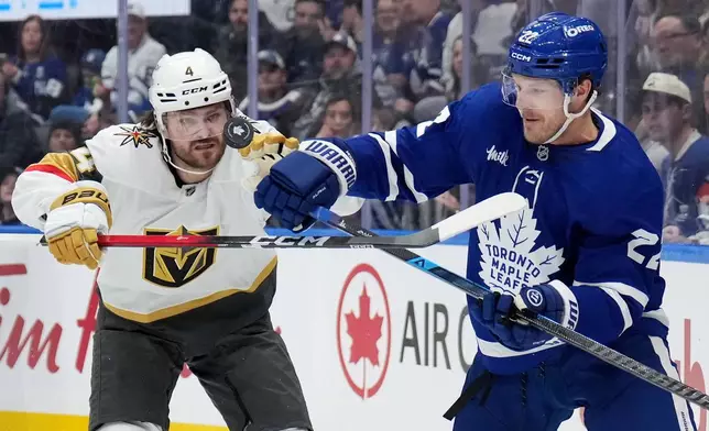 Vegas Golden Knights Rasmus Andersson (4) battles for the puck with Toronto Maple Leafs' Jake McCabe (22) during the second period of an NHL hockey game in Toronto on Friday, Jan. 23, 2026. (Nathan Denette/The Canadian Press via AP)