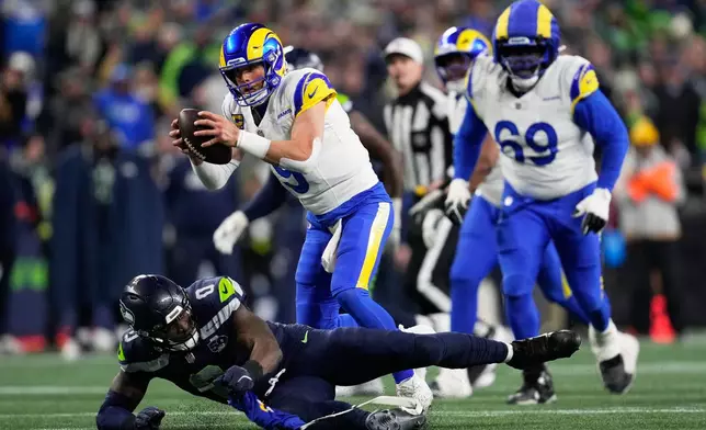 Los Angeles Rams quarterback Matthew Stafford (9) runs over Seattle Seahawks linebacker DeMarcus Lawrence (0) during the second half of the NFC Championship NFL football game Sunday, Jan. 25, 2026, in Seattle. (AP Photo/Godofredo A. Vásquez)