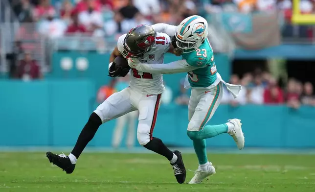 Miami Dolphins cornerback Jack Jones (23) tackles Tampa Bay Buccaneers wide receiver Jalen McMillan (11) during the first half of an NFL football game Sunday, Dec. 28, 2025, in Miami Gardens, Fla. (AP Photo/Lynne Sladky)