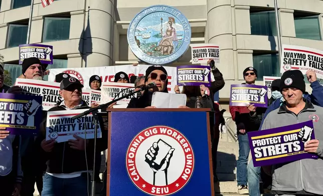 Demonstrators holds signs during a protest by Uber and Lyft drivers asking state regulators to take self-driving taxis off the streets due to safety concerns at the California Public Utilities Commission headquarters Friday, Jan. 9, 2026, in San Francisco. (AP Photo/Haven Daley)