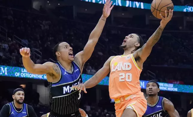 Cleveland Cavaliers guard Jaylon Tyson (20) goes to the basket in front of Orlando Magic guard Desmond Bane (3) in the first half of an NBA basketball game in Cleveland, Monday, Jan. 26, 2026. (AP Photo/Sue Ogrocki)