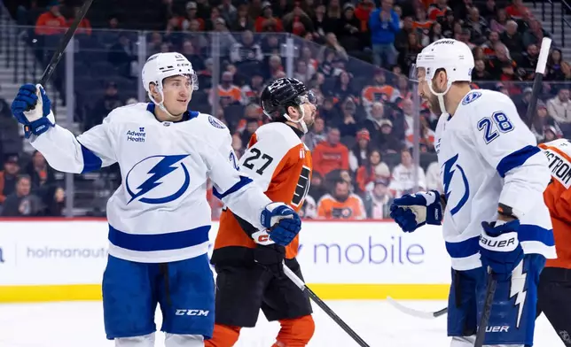 Tampa Bay Lightning's Pontus Holmberg, left, reacts to his goal with Zemgus Girgensons, right, as Philadelphia Flyers' Noah Cates, center, skates by during the first period of an NHL hockey game, Monday, Jan. 12, 2026, in Philadelphia. (AP Photo/Chris Szagola)