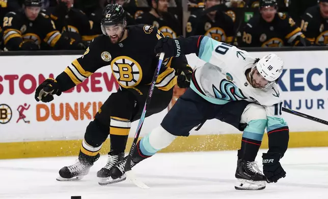 Boston Bruins' Mark Kastelic eyes a loose puck as he gets past Seattle Kraken's Matty Beniers during the second period of an NHL hockey game Thursday, Jan. 15, 2026, in Boston. (AP Photo/Winslow Townson)