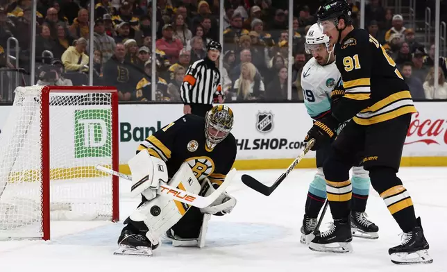 Boston Bruins goaltender Jeremy Swayman makes a save as defenseman Nikita Zadorov and Seattle Kraken's Frederick Gaudreau look for the rebound during the first period of an NHL hockey game, Thursday, Jan. 15, 2026, in Boston. (AP Photo/Winslow Townson)