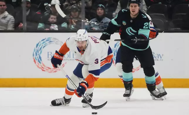 New York Islanders defenseman Adam Pelech (3) moves the puck against Seattle Kraken right wing Eeli Tolvanen, back, during the first period of an NHL hockey game Wednesday, Jan. 21, 2026, in Seattle. (AP Photo/Lindsey Wasson)