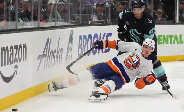 New York Islanders center Kyle MacLean, front, falls against Seattle Kraken defenseman Jamie Oleksiak, back, during the second period of an NHL hockey game Wednesday, Jan. 21, 2026, in Seattle. (AP Photo/Lindsey Wasson)