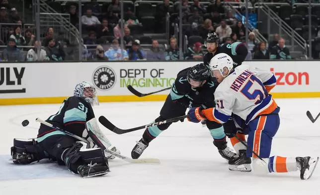 New York Islanders left wing Emil Heineman (51) makes a shot against Seattle Kraken goaltender Philipp Grubauer (31) as defenseman Vince Dunn (29) looks on during the second period of an NHL hockey game Wednesday, Jan. 21, 2026, in Seattle. (AP Photo/Lindsey Wasson)