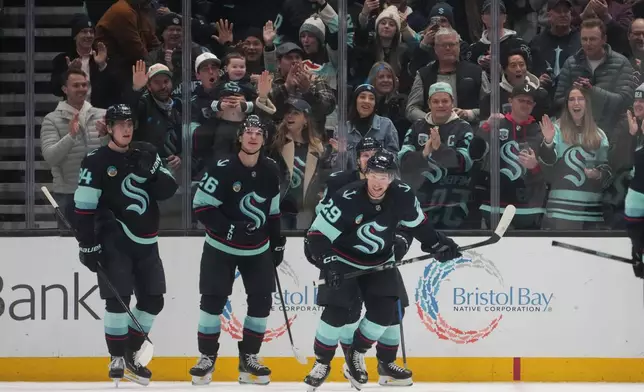 Seattle Kraken defenseman Vince Dunn (29) skates back to the bench after celebrating his goal against the New York Islanders with right wing Kaapo Kakko (84) and center Ryan Winterton (26) during the second period of an NHL hockey game Wednesday, Jan. 21, 2026, in Seattle. (AP Photo/Lindsey Wasson)