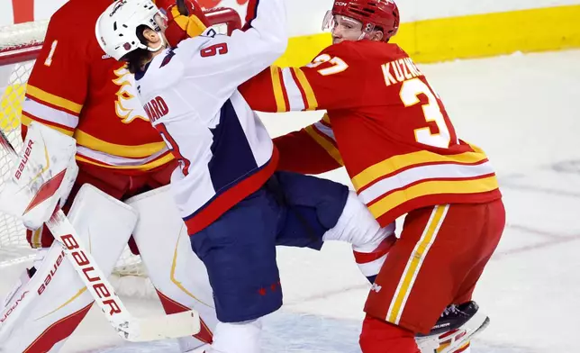 Washington Capitals' Ryan Leonard, front left, and Calgary Flames' Yan Kuznetsov, right, battle in front of the Flames' net during second-period NHL hockey game action in Calgary, Alberta, Friday, Jan. 23, 2026. (Larry MacDougal/The Canadian Press via AP)
