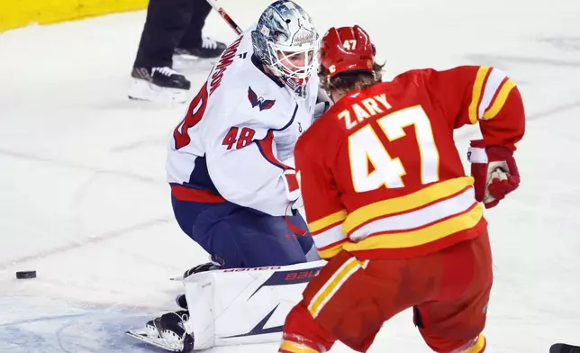 Washington Capitals goalie Logan Thompson (48) makes a save against Calgary Flames' Connor Zary (47) during first-period NHL hockey game action in Calgary, Alberta, Friday, Jan. 23, 2026. (Larry MacDougal/The Canadian Press via AP)