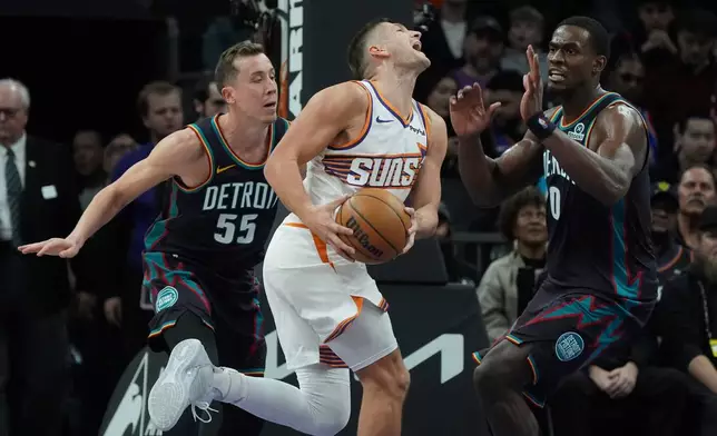 Phoenix Suns guard Grayson Allen, center, is fouled by Detroit Pistons forward Duncan Robinson (55) as Pistons center Jalen Duren (0) arrives to defend during the first half of an NBA basketball game Thursday, Jan. 29, 2026, in Phoenix. (AP Photo/Ross D. Franklin)