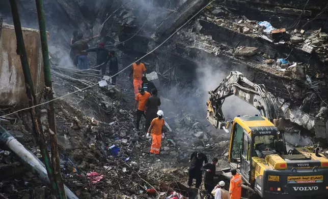 Rescue workers and firefighters with heavy machinery conduct a search operation at a burnt building of a multi-story shopping plaza following a massive fire in Karachi, Pakistan, Wednesday, Jan. 21, 2026. (AP Photo/Ali Raza)