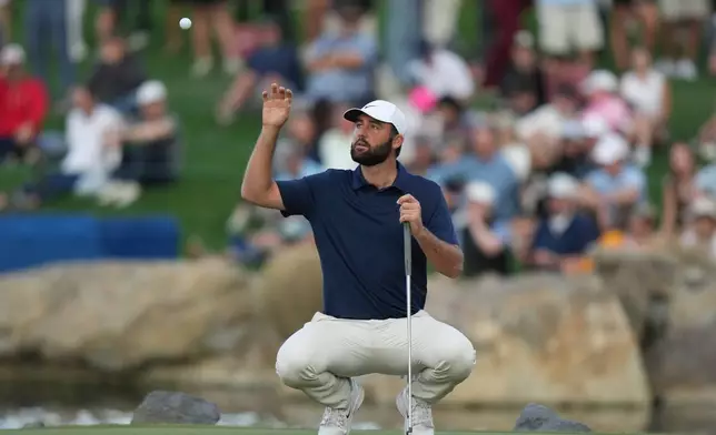 Scottie Scheffler reaches up to catch his golf ball his caddie tossed to him at the 18th green during the third round of the American Express golf event on the Pete Dye Stadium Course at PGA West Saturday, Jan. 24, 2026, in La Quinta, Calif. (AP Photo/Ross D. Franklin)