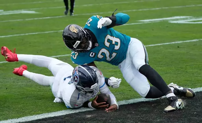 Tennessee Titans quarterback Cam Ward (1) scores a touchdown as he is hit by Jacksonville Jaguars linebacker Foyesade Oluokun (23) during the first half of an NFL football game Sunday, Jan. 4, 2026, in Jacksonville, Fla. (AP Photo/John Raoux)