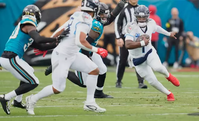 Tennessee Titans quarterback Cam Ward (1) runs the ball past Jacksonville Jaguars defensive end Travon Walker (44) during the first half of an NFL football game Sunday, Jan. 4, 2026, in Jacksonville, Fla. (AP Photo/John Raoux)