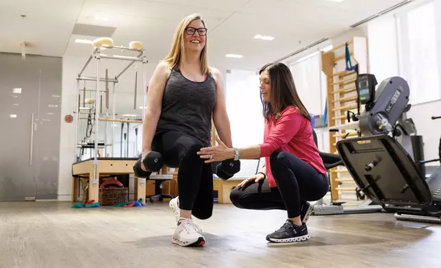 Sarah Baldassaro, left, demonstrates a strength-training regimen with her trainer, Hilary Granat, at the Center for Orthopedic Rehab and Exercise on Thursday, Jan. 8, 2026, in Washington. (AP Photo/Moriah Ratner)