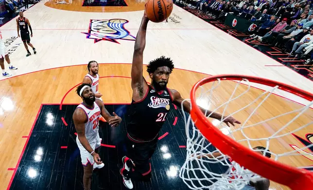 Philadelphia 76ers' Joel Embiid, center, goes up for the shot as New York Knicks' Mitchell Robinson, left, and Miles McBride, right, looks on during the first half of an NBA basketball game, Saturday, Jan. 24, 2026, in Philadelphia. (AP Photo/Chris Szagola)