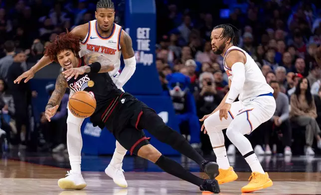 Philadelphia 76ers' Kelly Oubre Jr., left, tries to regain control of the loose ball as New York Knicks' Miles McBride, center, and Jalen Brunson, right, defending during the first half of an NBA basketball game, Saturday, Jan. 24, 2026, in Philadelphia. (AP Photo/Chris Szagola)