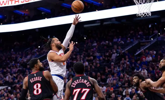 New York Knicks' Jalen Brunson, center, goes up for the shot over Philadelphia 76ers' Paul George, left, and VJ Edgecombe, right, during the first half of an NBA basketball game, Saturday, Jan. 24, 2026, in Philadelphia. (AP Photo/Chris Szagola)