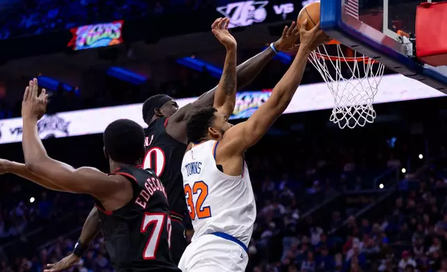 New York Knicks' Karl-Anthony Towns, right, goes up for the shot as Philadelphia 76ers' Adem Bona, center, fouls him with VJ Edgecombe, left, defending during the first half of an NBA basketball game, Saturday, Jan. 24, 2026, in Philadelphia. (AP Photo/Chris Szagola)