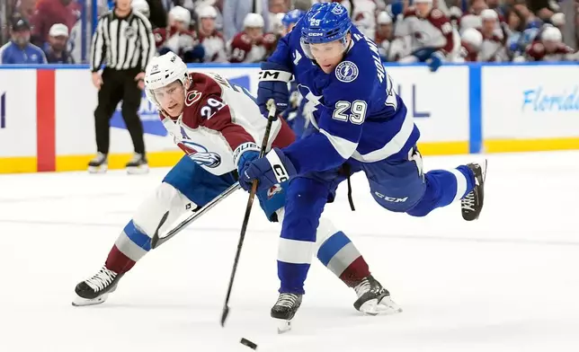 Colorado Avalanche center Nathan MacKinnon (29, left) blocks a shot by Tampa Bay Lightning right wing Pontus Holmberg (29) during the second period of an NHL hockey game Tuesday, Jan. 6, 2026, in Tampa, Fla. (AP Photo/Chris O'Meara)