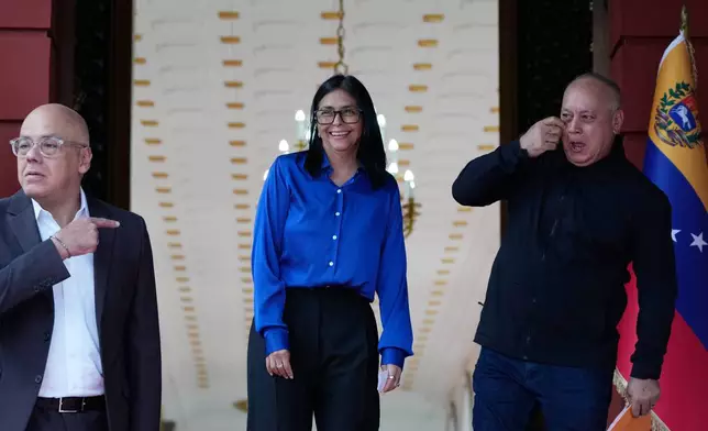 Venezuela's acting President Delcy Rodriguez, center, smiles flanked by Interior Minister Diosdado Cabello, right, and National Assembly President Jorge Rodriguez after making a statement to the press at Miraflores presidential palace in Caracas, Venezuela, Wednesday, Jan. 14, 2026. (AP Photo/Ariana Cubillos)