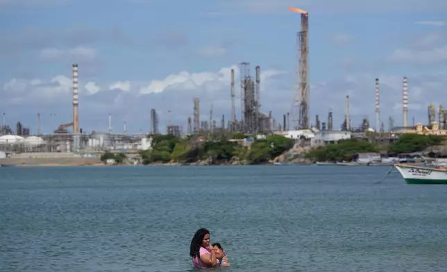 Ceylis Mendez and her daughter Zoe cool off in the Gulf of Venezuela in front of the Cardon oil refinery off the shore of Punta Cardon, Venezuela, Wednesday, Jan. 14, 2026. (AP Photo/Matias Delacroix)