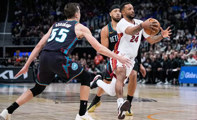 Miami Heat guard Norman Powell, right, drives past Detroit Pistons forward Duncan Robinson, left, and guard Cade Cunningham during the first half of an NBA basketball game, Thursday, Jan. 1, 2026, in Detroit. (AP Photo/Ryan Sun)