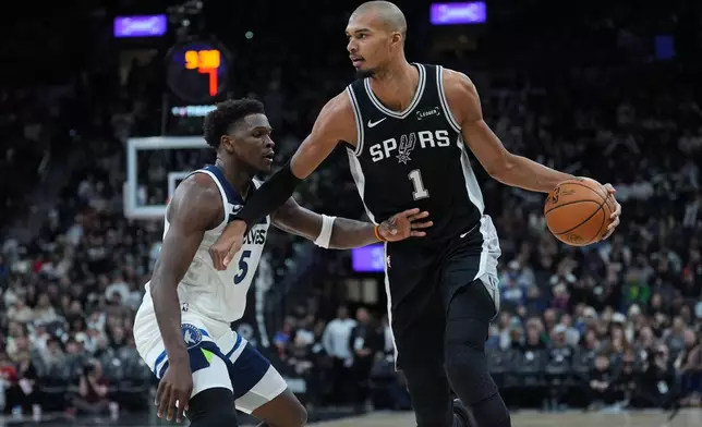 San Antonio Spurs forward Victor Wembanyama (1) drives against Minnesota Timberwolves guard Anthony Edwards (5) during the second half of an NBA basketball game in San Antonio, Saturday, Jan. 17, 2026. (AP Photo/Eric Gay)