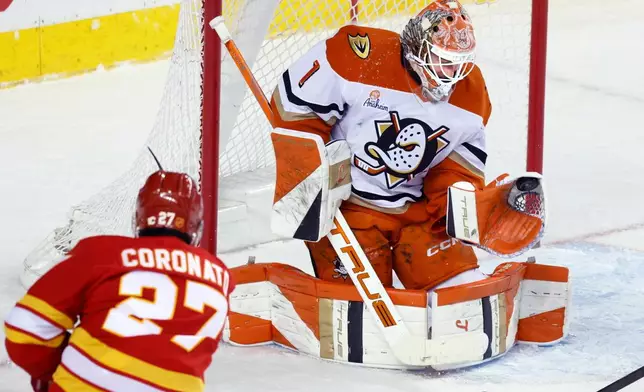 Anaheim Ducks goalie Lukas Dostal (1) makes a save against Calgary Flames' Matt Coronato (27) during first-period NHL hockey game action in Calgary, Alberta, Sunday, Jan. 25, 2026. (Larry MacDougal/The Canadian Press via AP)
