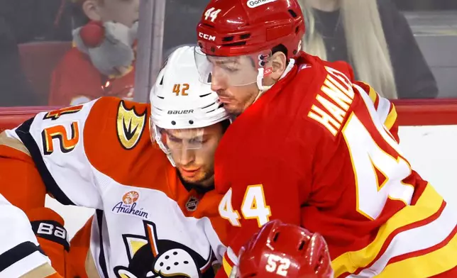 Anaheim Ducks' Tim Washe (42) battles with Calgary Flames' Joel Hanley (44) during second-period NHL hockey game action in Calgary, Alberta, Sunday, Jan. 25, 2026. (Larry MacDougal/The Canadian Press via AP)