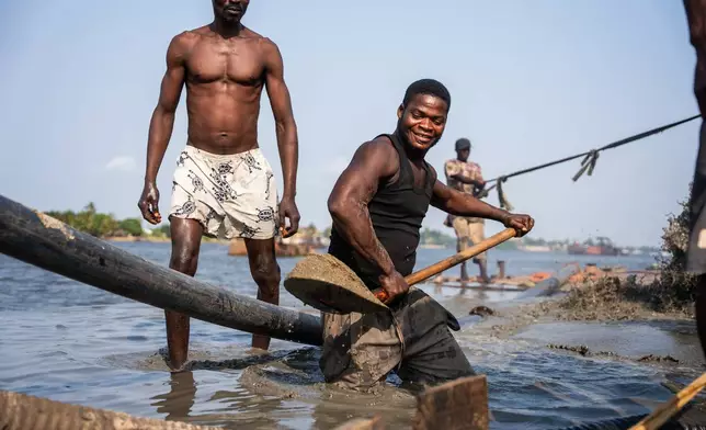 Worker shovels up freshly extracted sharp sand from a dredging transporter in Ibeshe, Lagos, Nigeria, on Saturday, Dec. 6, 2025. (AP Photo/Grace Ekpu)
