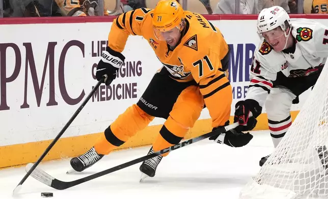 Pittsburgh Penguins' Evgeni Malkin (71) controls the puck with Chicago Blackhawks' Oliver Moore, right, defending during the second period of an NHL hockey game in Pittsburgh, Thursday, Jan. 29, 2026. (AP Photo/Gene J. Puskar)